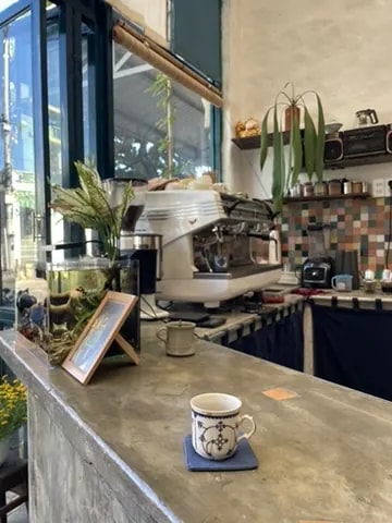 A small patterned coffee cup on a concrete café counter beside an espresso machine.