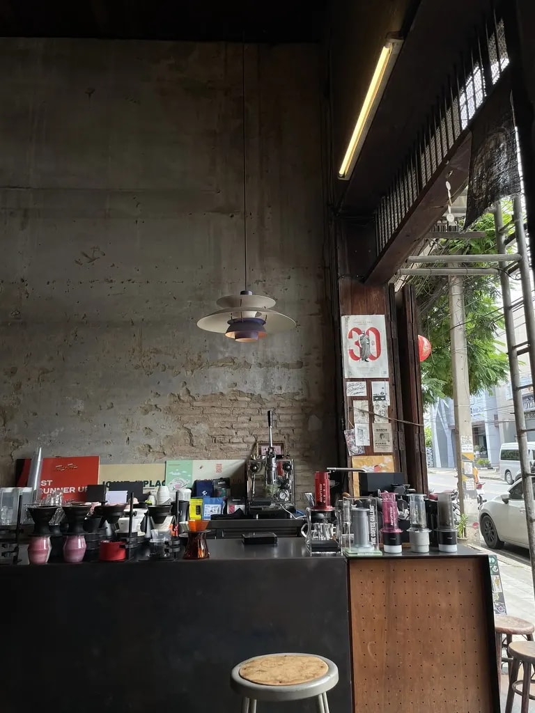 An open industrial café counter with grinders, brewers, and a street view.