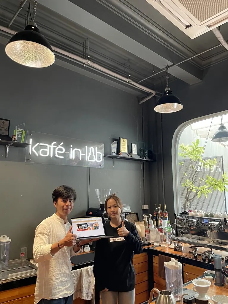 Two people smiling beside the espresso bar at Kafe in LAB.