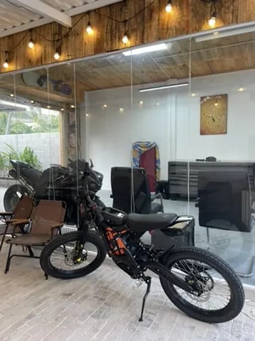 A glass-fronted café with motorcycles parked outside and a small seating area.