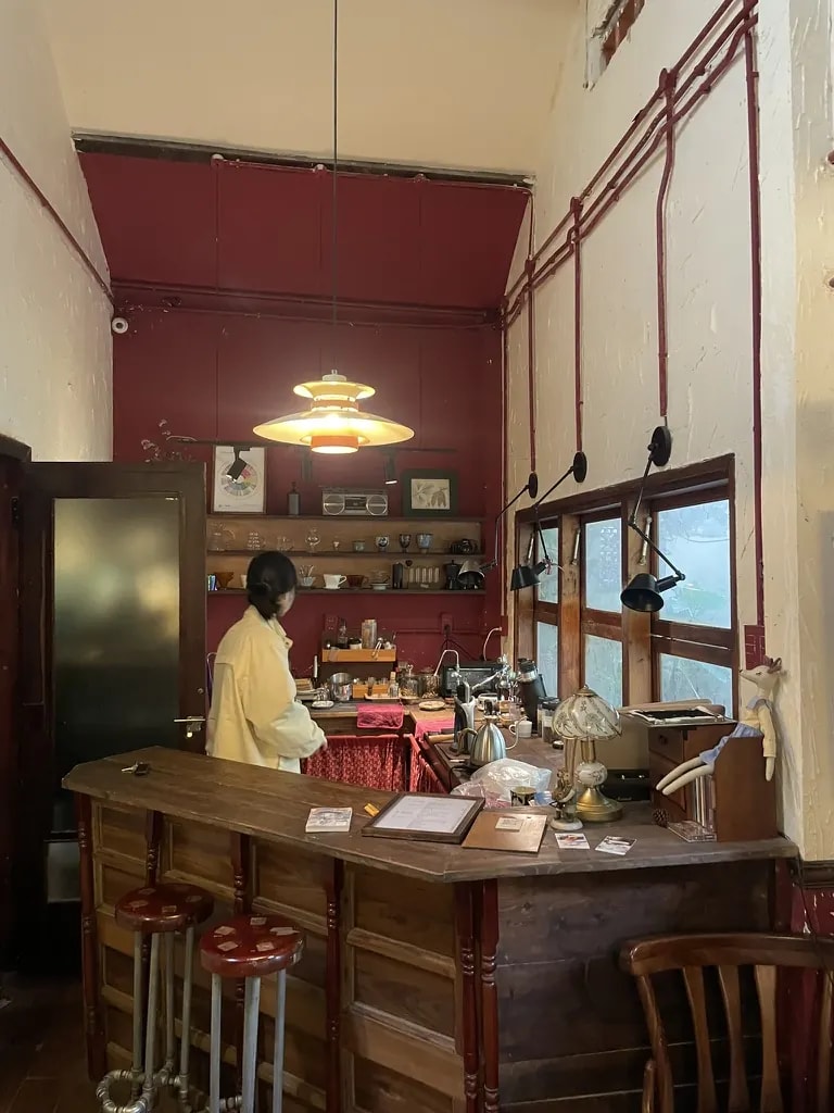 A red-walled vintage café bar with pendant lights and a wooden counter.