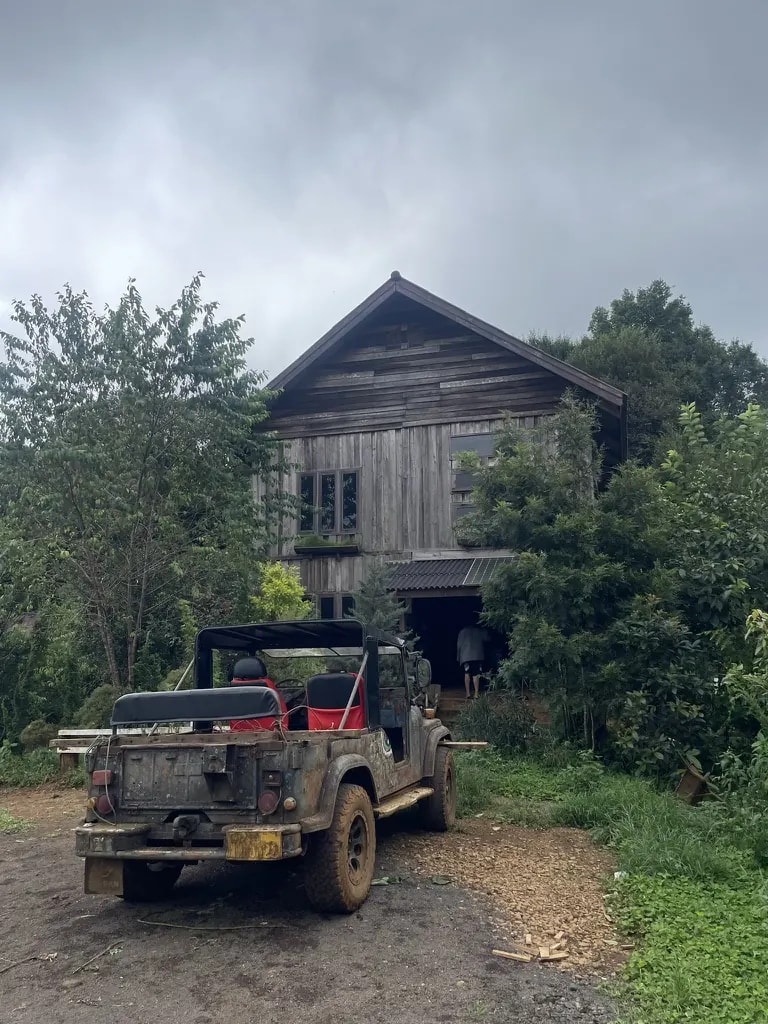 A rustic wooden coffee house in the hills with an old jeep outside.