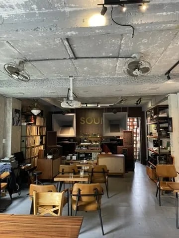 A café interior with records, books, lounge seating, and wooden tables.