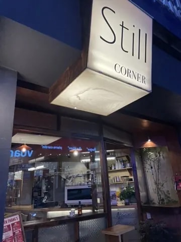 The Still Corner café storefront glowing at night.
