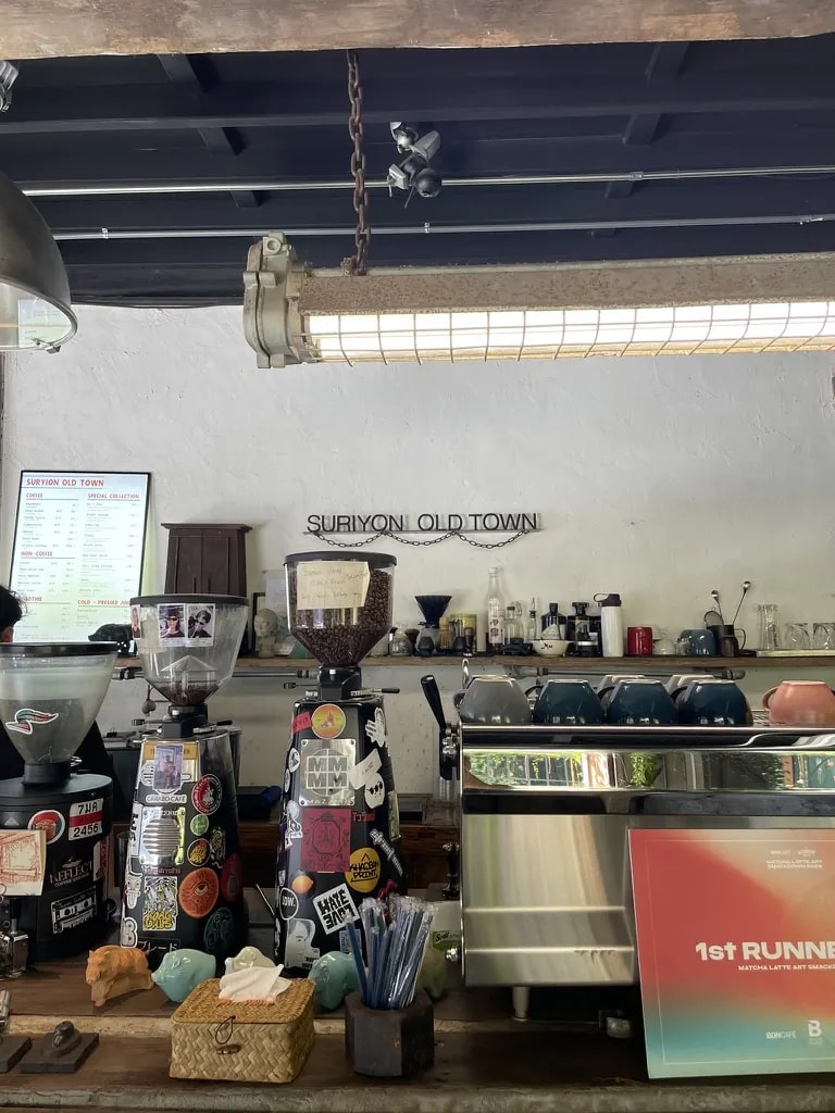 The Suriyon Old Town coffee counter with grinders, menus, and an espresso machine.