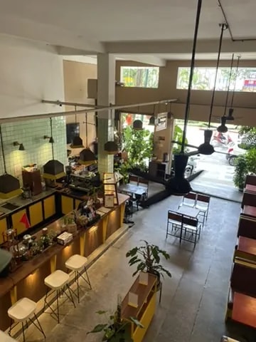 A two-storey café viewed from above, with a central bar and tables below.