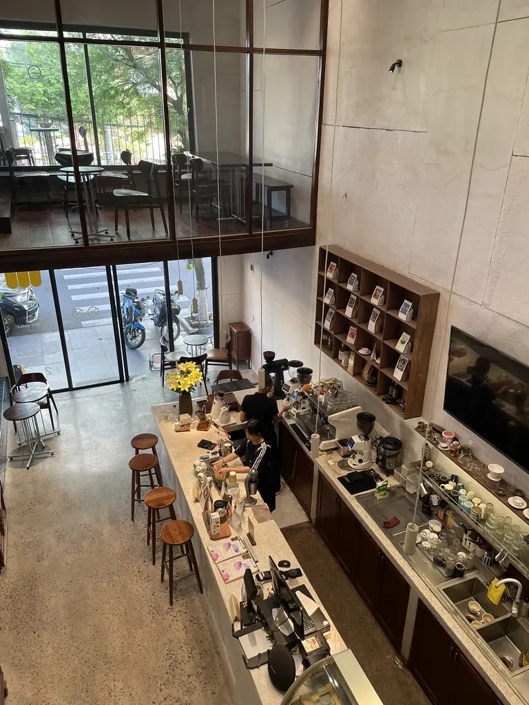 A two-storey café and roastery viewed from above, with a long central bar.