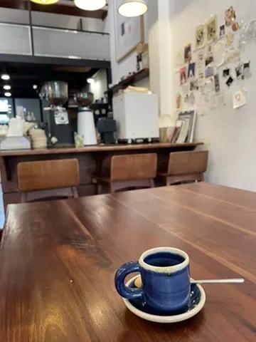 A small blue espresso cup on a long wooden café table.
