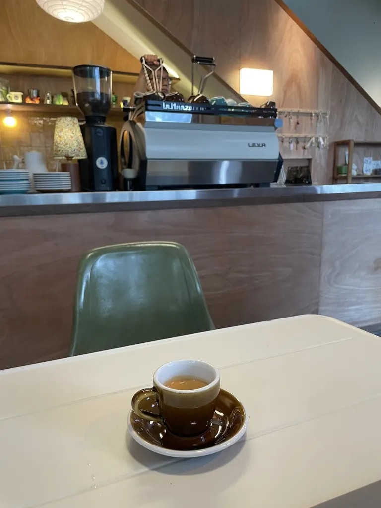A brown espresso cup on a table facing a café espresso machine.