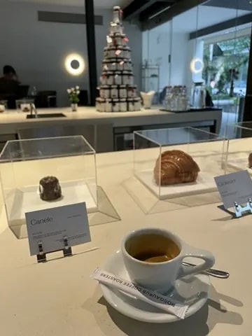 An espresso cup at a white counter displaying individual pastries.