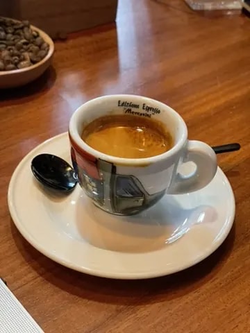 Espresso in a decorated Italian cup on a wooden table.