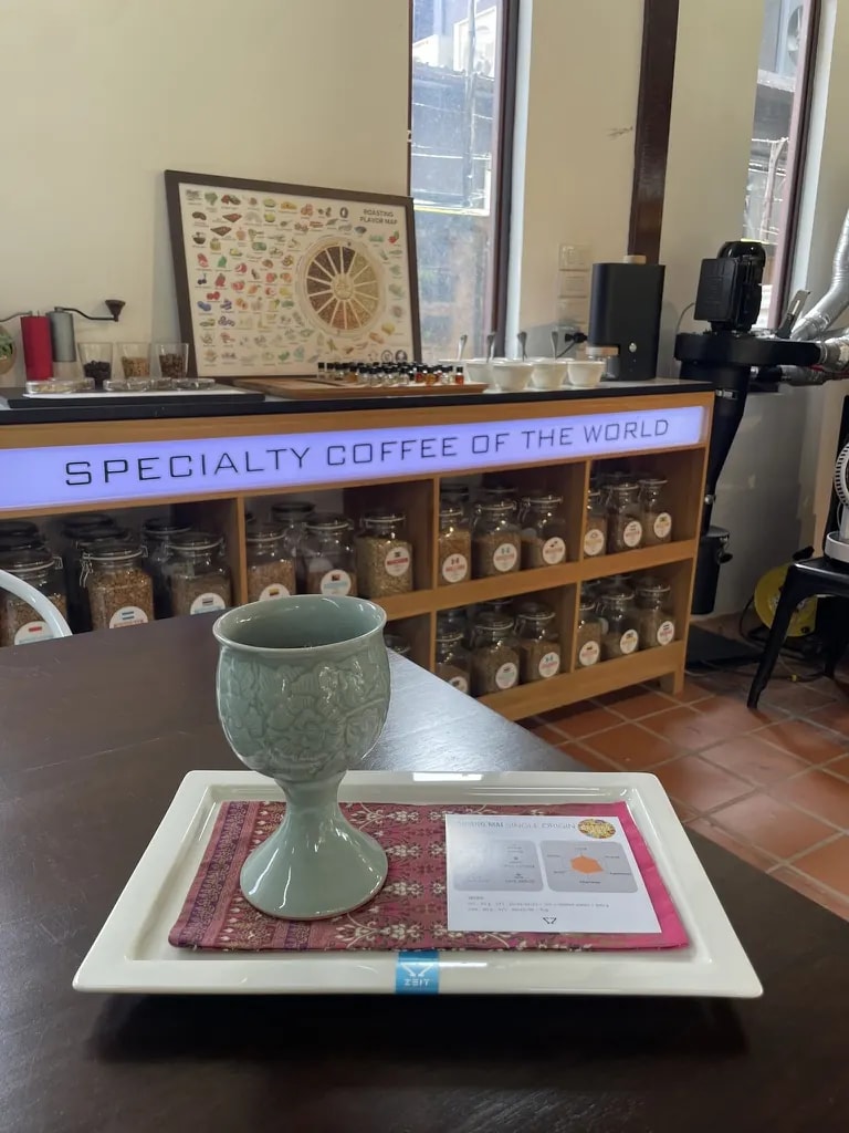 A specialty coffee tasting served in a celadon goblet with an origin card.